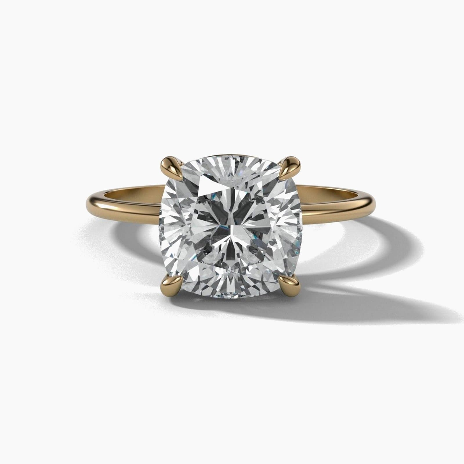 Thin solitaire engagement ring with a cushion cut diamond in yellow gold