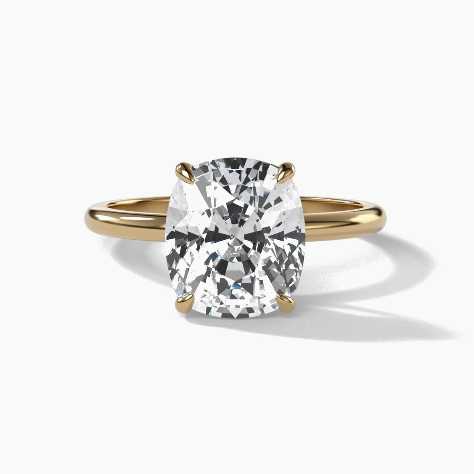 Thin solitaire engagement ring with an elongated cushion cut diamond in yellow gold