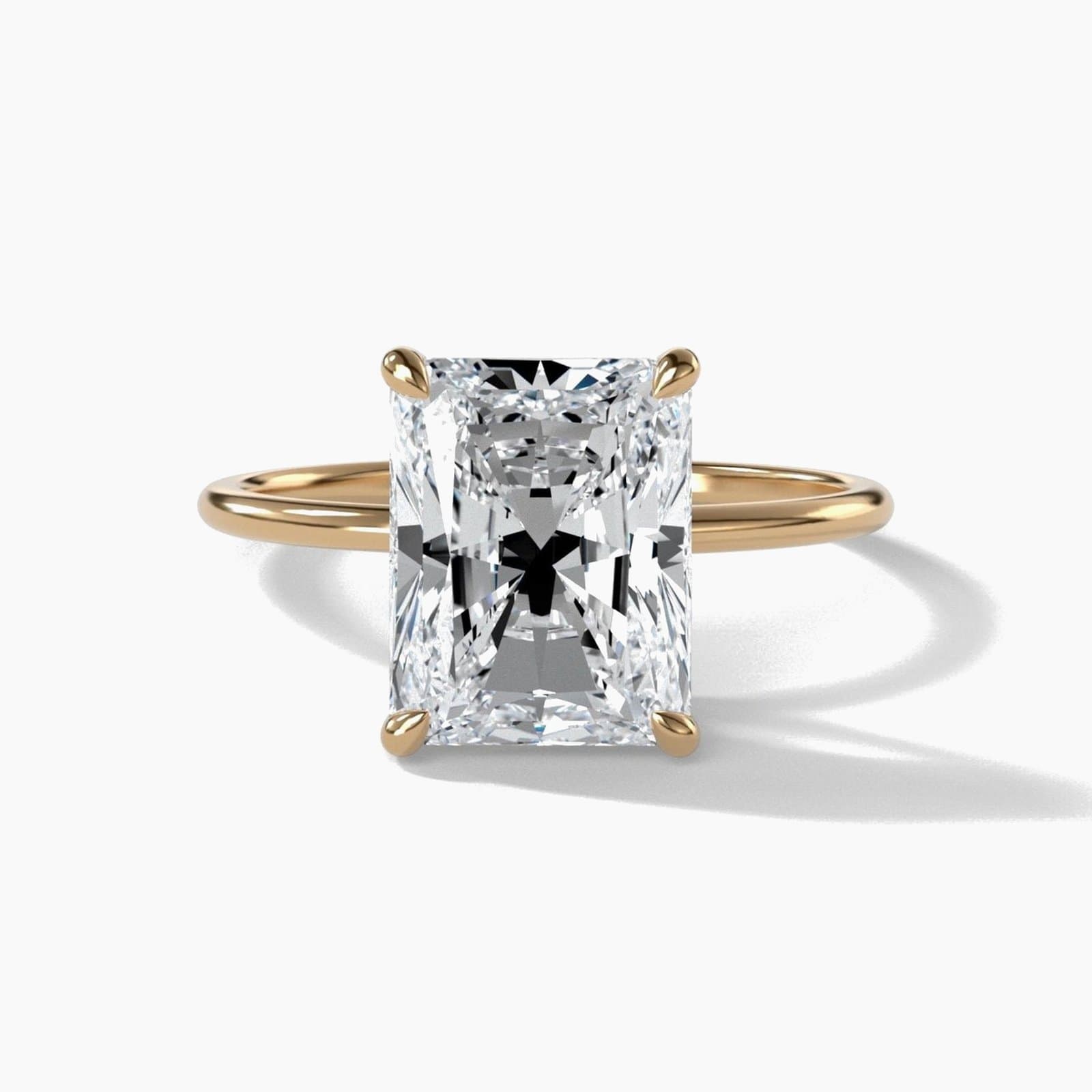 Thin solitaire engagement ring with an elongated radiant cut diamond in yellow gold