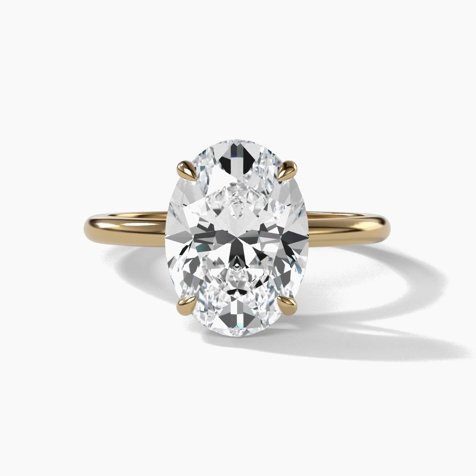 Thin solitaire engagement ring with an oval diamond in yellow gold