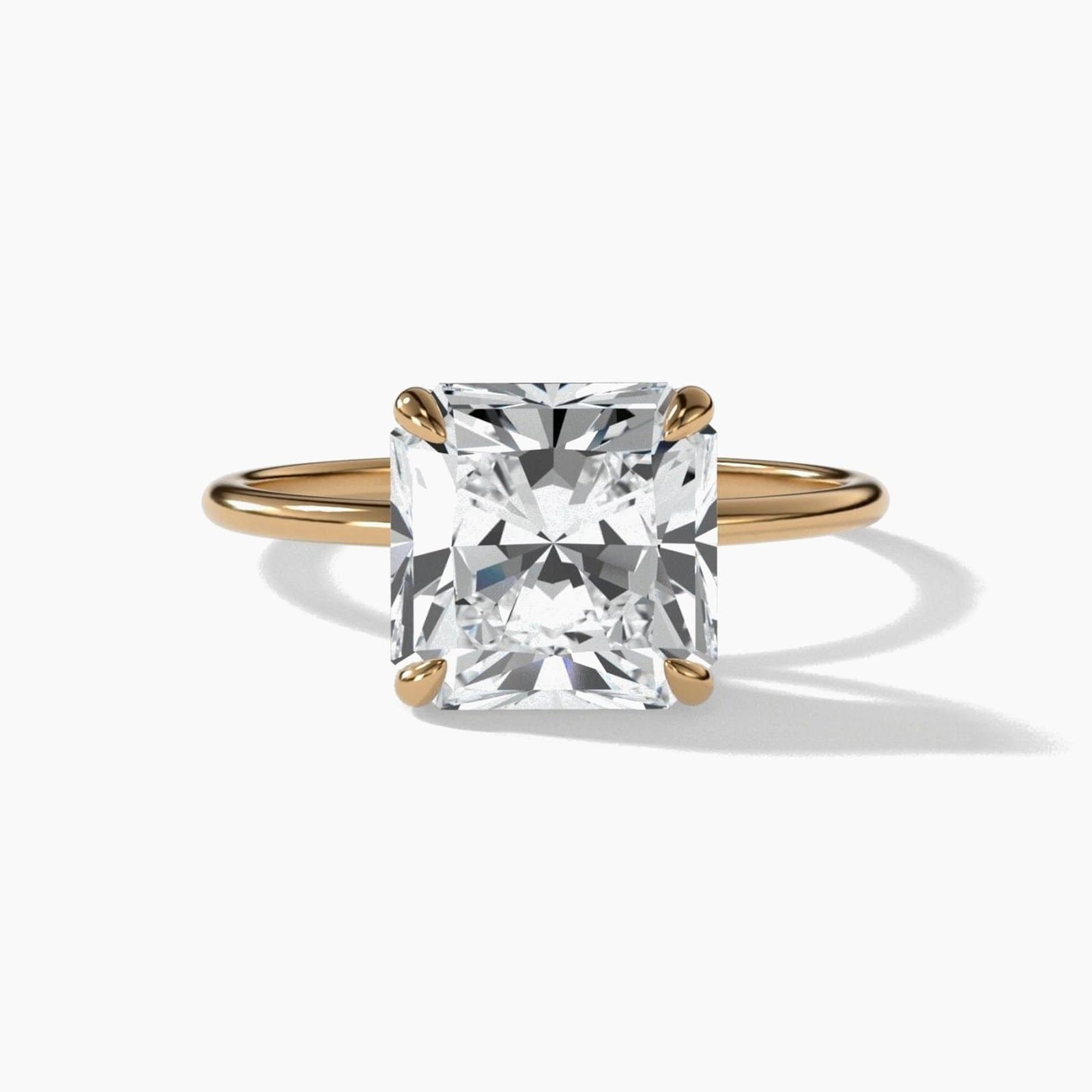 Thin solitaire engagement ring with a radiant cut diamond in yellow gold